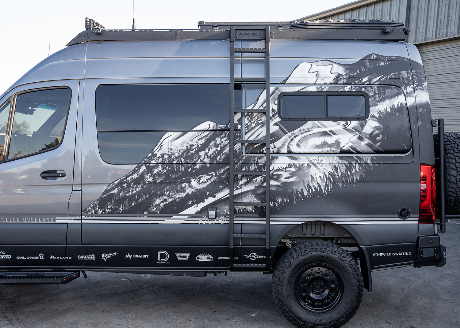 Full view of ROAMBUILT Flatpack Ladder mounted on a Mercedes Sprinter van, showing all-aluminum construction and wide, notched traction steps.