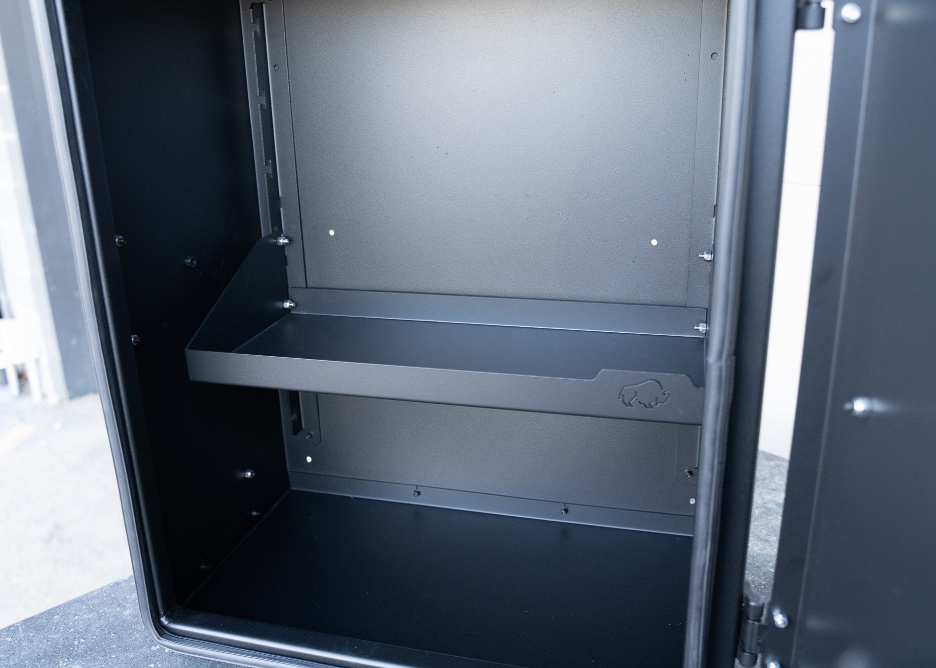 Close-up view inside the ROAMBUILT Universal Aluminum Storage Box featuring the adjustable shelf, black powder-coated interior, and durable construction details.