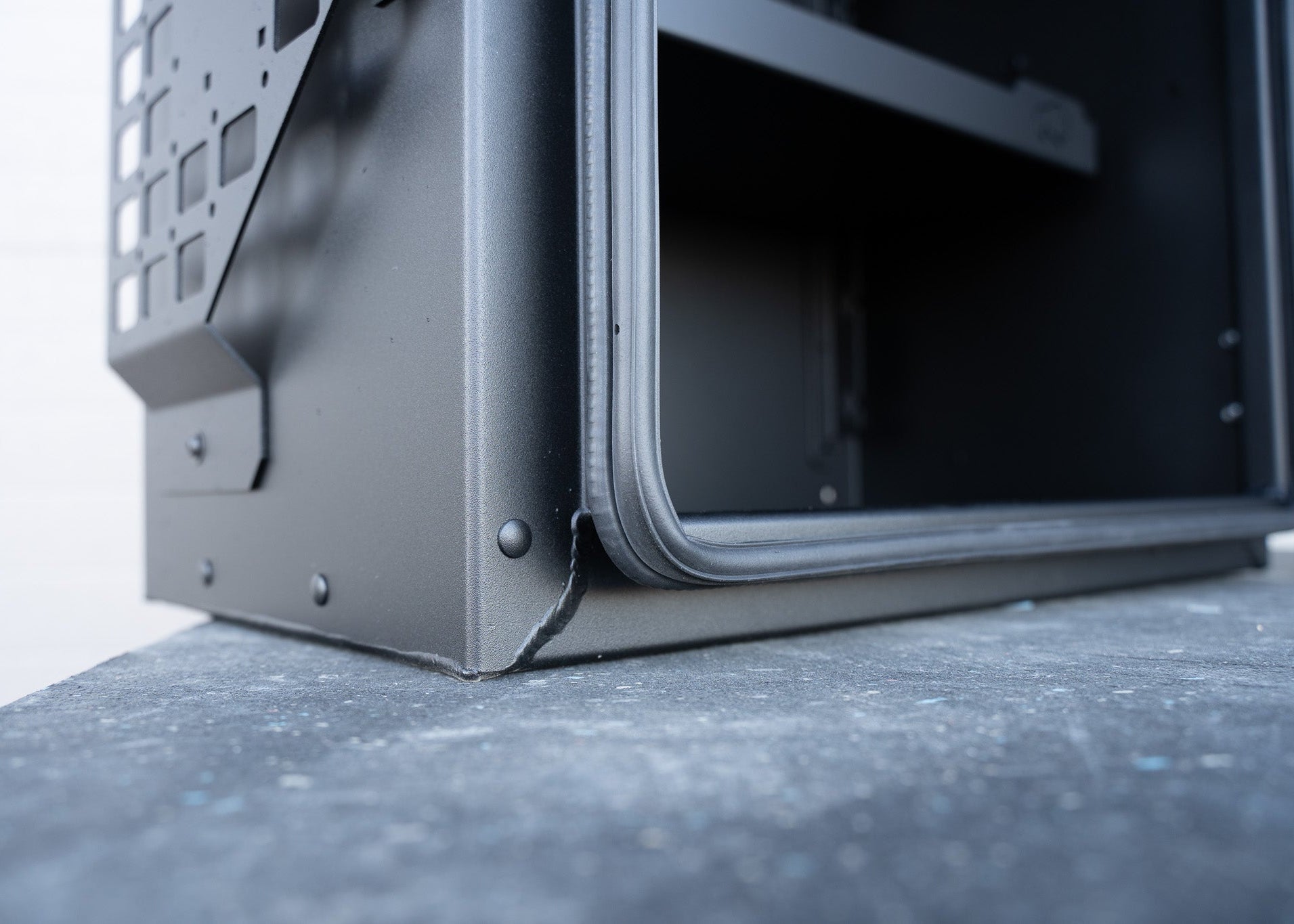 Close-up view of ROAMBUILT Universal Aluminum Storage Box showing detailed welds and black automotive-grade gasket along the door edge for water and dust sealing.