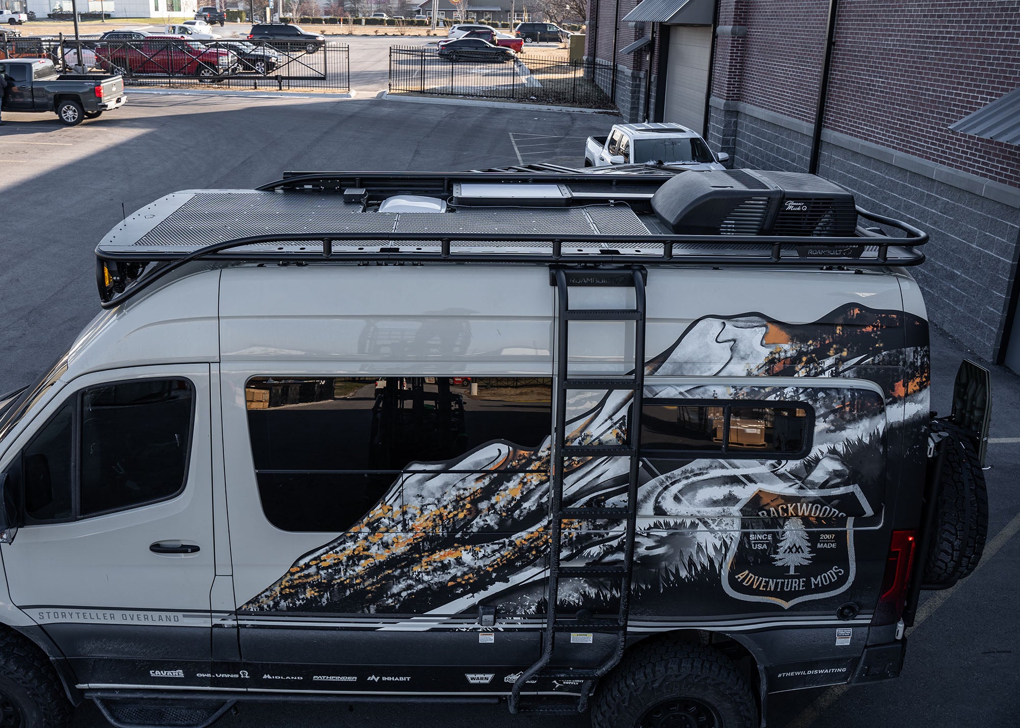 Driver side view of the entire ROAMBUILT Safari 2.0 roof rack from front to back, featuring the integrated chicane ladder mounted alongside for easy roof access.
