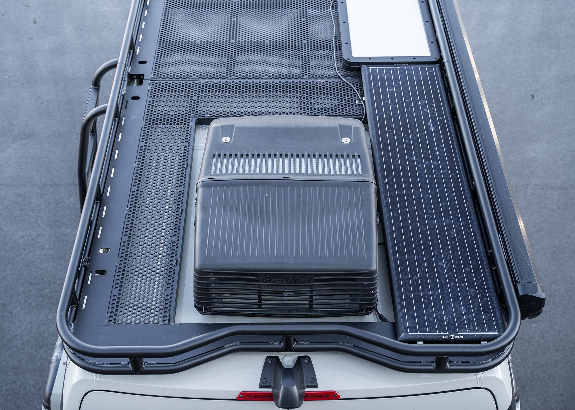 View of the back portion of the ROAMBUILT Safari 2.0 roof rack, highlighting the cutout for the A/C unit, the curved rear design to accommodate the rear camera, and the mounted solar panel.