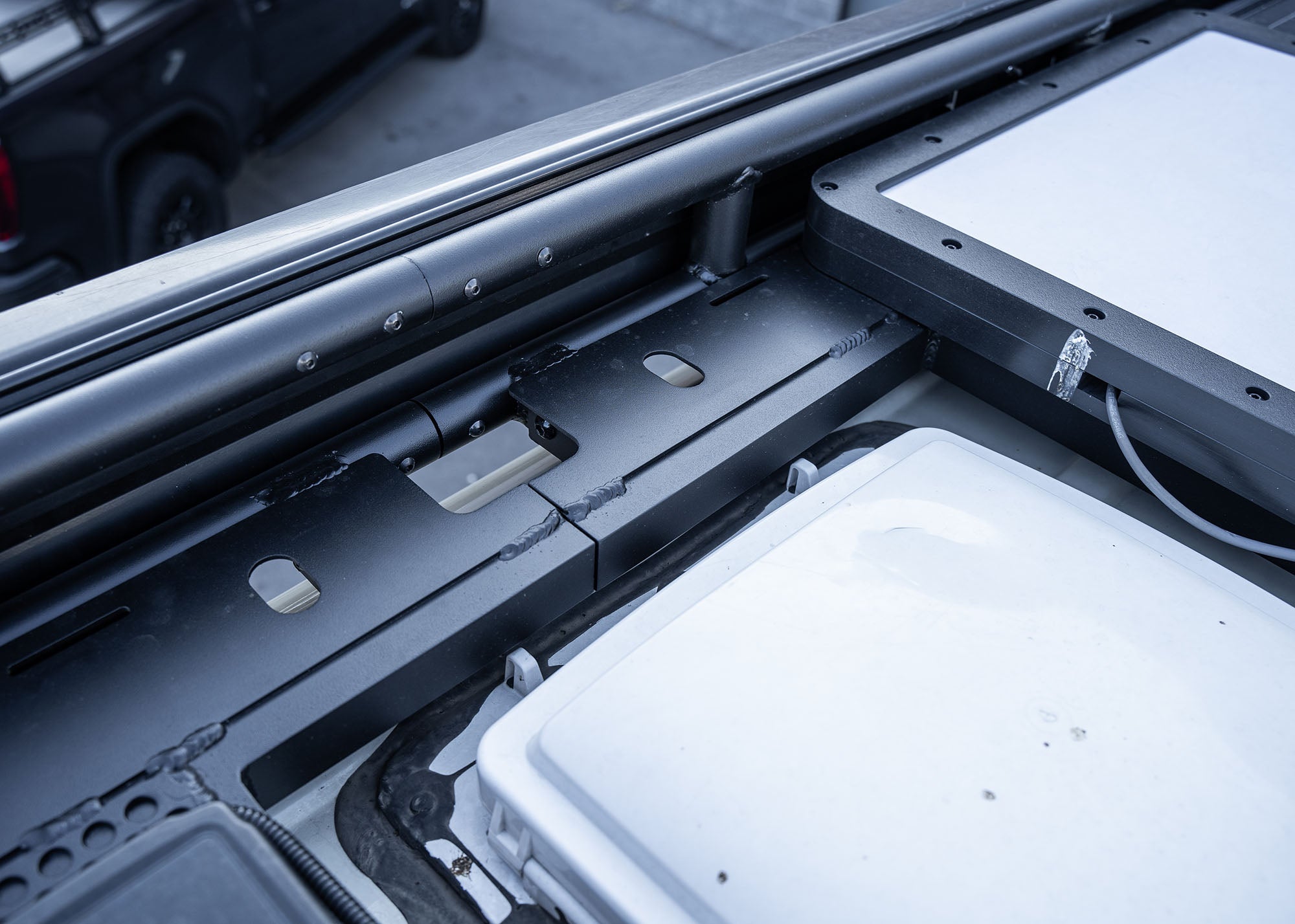 Close-up view of Safari 2.0 roof rack mounting connection between rack sections and into factory roof railing, positioned behind the awning.