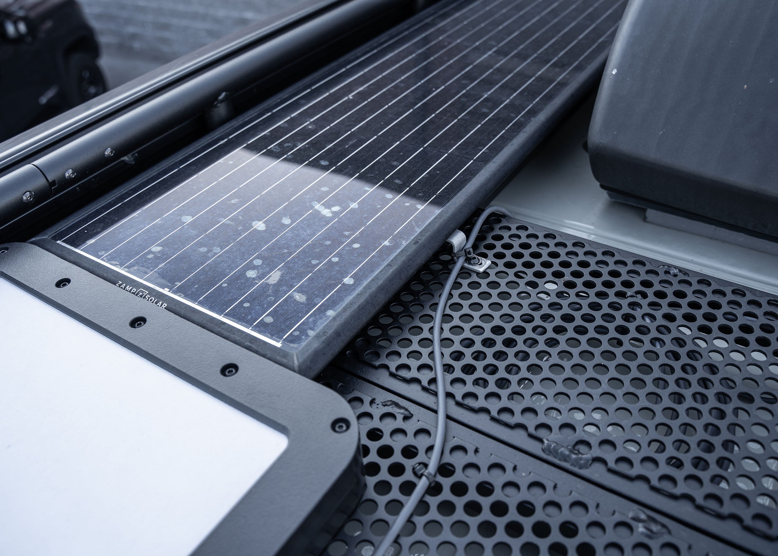 Close-up view of the ROAMBUILT Safari 2.0 roof rack showing the Starlink satellite dish and Zamp Solar panel securely mounted for reliable connectivity and off-grid power.