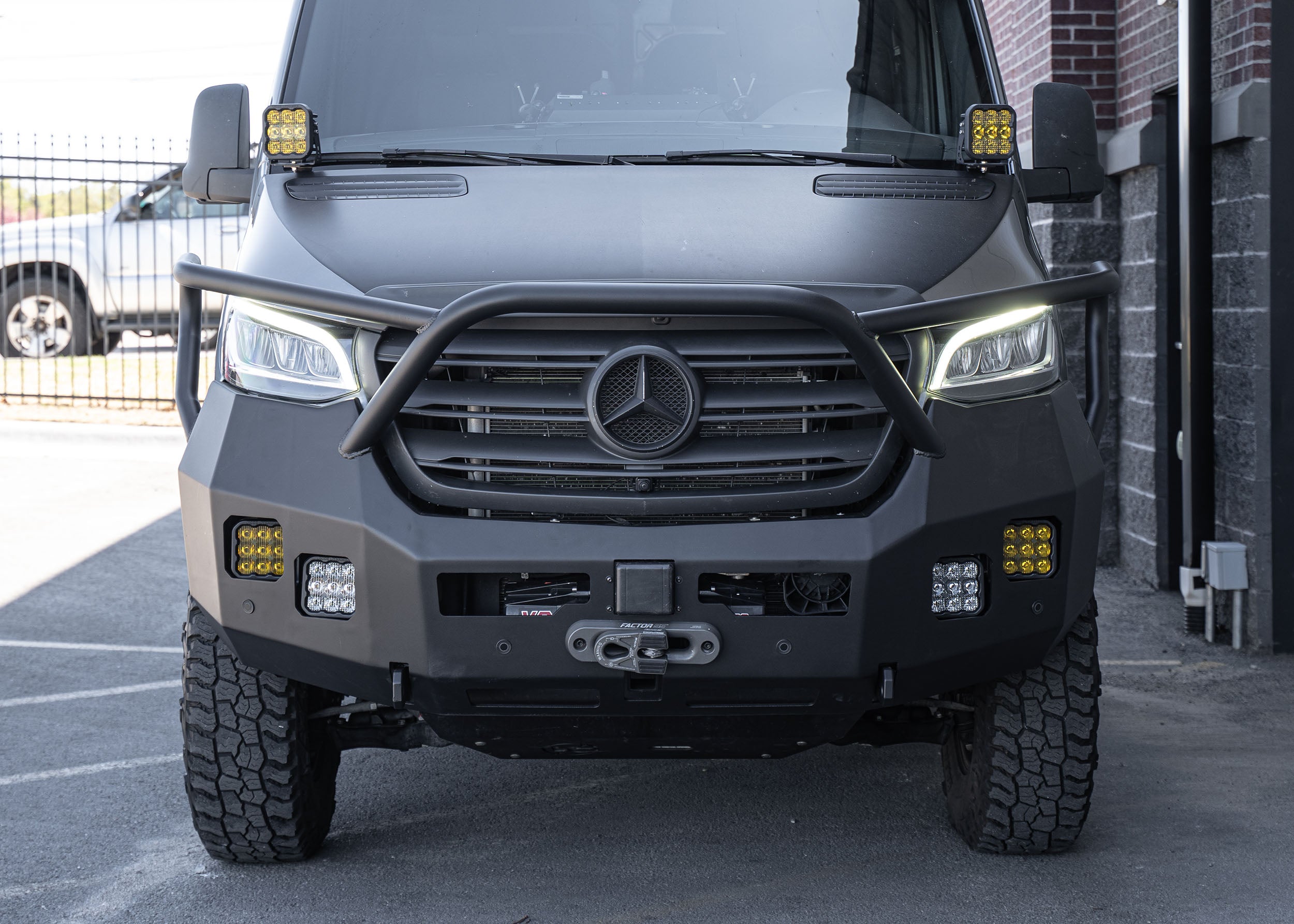 Front view of a Mercedes Sprinter van equipped with the Full Guard Front Bumper, showcasing its hybrid steel and aluminum construction, integrated winch mount, shackle points, and light pockets—designed for maximum protection and off-road performance with a clean, functional aesthetic.