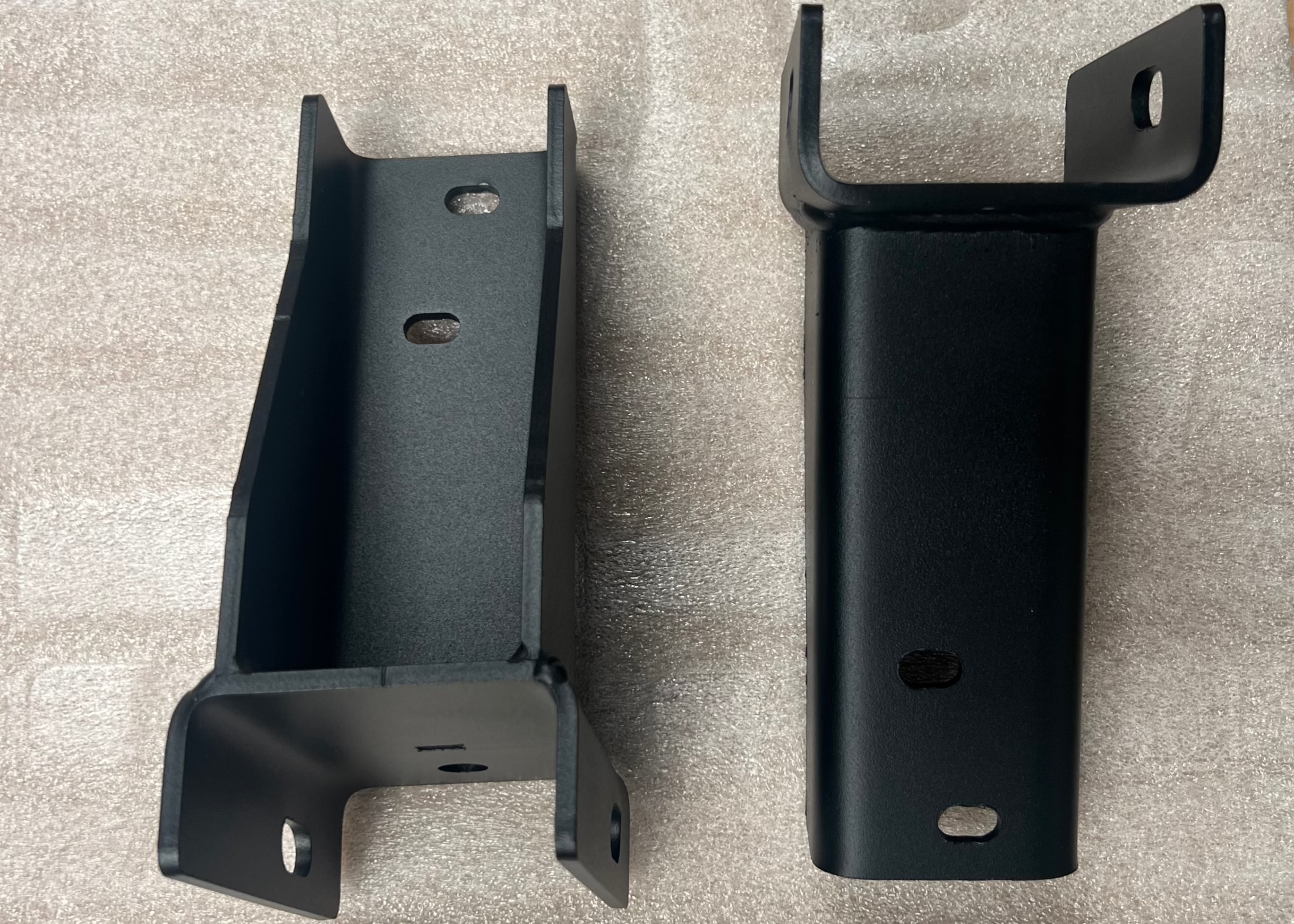 Top and bottom views of a pair of ROAMBUILT replacement frame brackets for 2019+ Mercedes Sprinter 2WD and 3500 dually models, showing mounting holes, structural design, and weld details.