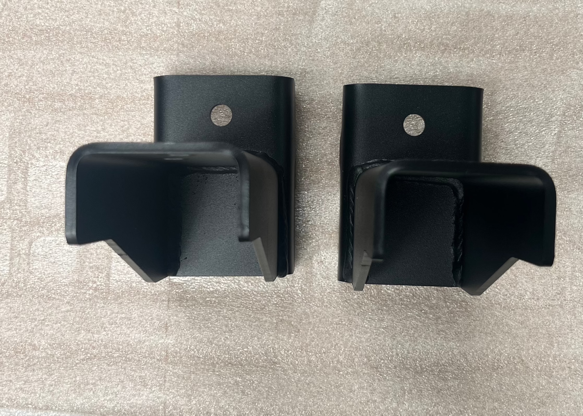 View looking down at a pair of ROAMBUILT replacement frame brackets for 2019+ Mercedes Sprinter 2WD and 3500 dually models, showing the flat mounting surfaces and bolt holes.