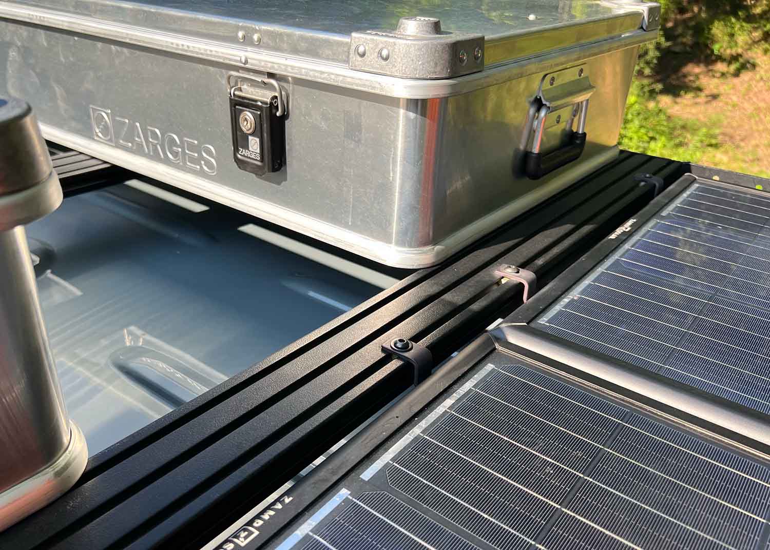 Close-up view of solar panel securely mounted to a ROAMBUILT Flatpack Roof Rack extrusion using black oxide bolts, lock washers, and slide-in T-nuts.