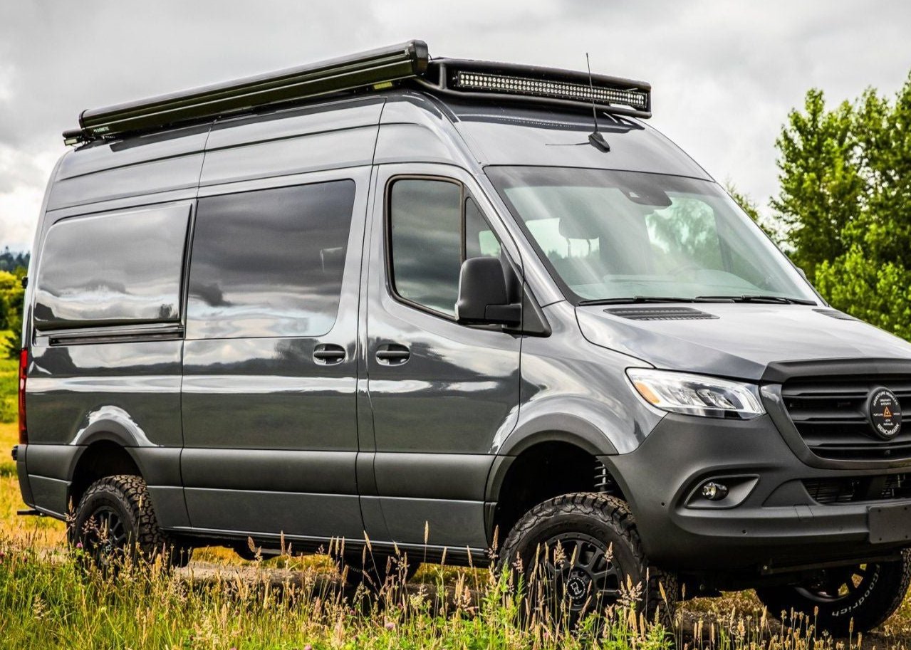 Passenger side view of SafariRack 2.0 SLB mounted on a 2007+ Mercedes Sprinter van, showing curved front profile, perforated decking, and rugged aluminum design.