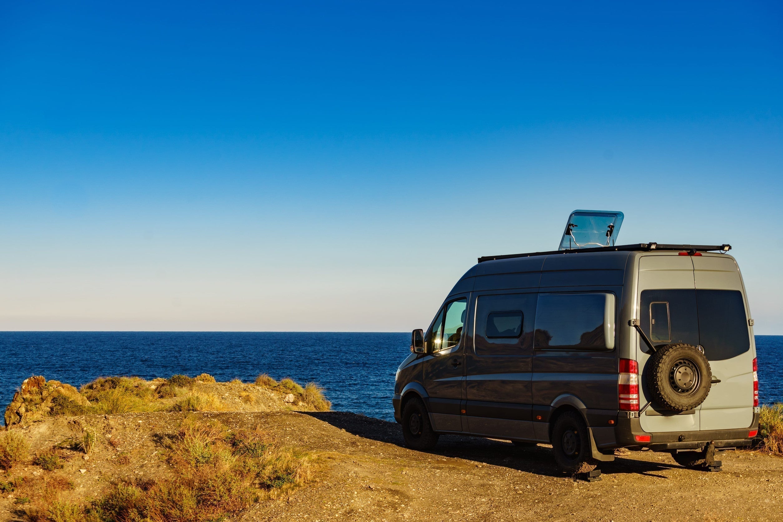 Campervan rv sitting on the shore by the ocean